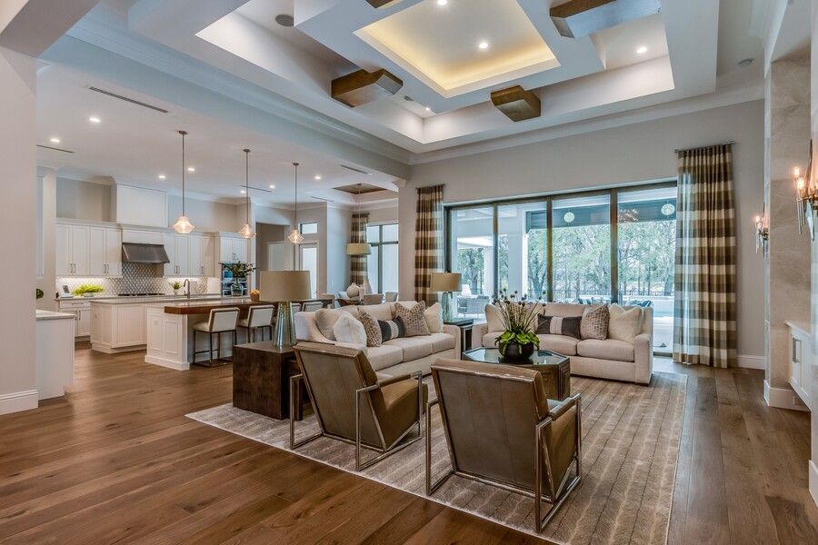 Spacious open-concept living room and kitchen with coffered ceiling, large windows, and modern furnishings