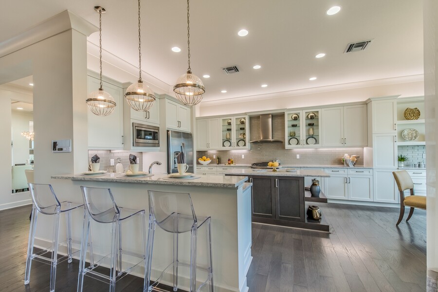 Spacious remodeled kitchen with white cabinets, island seating, pendant lights, and stainless steel appliances