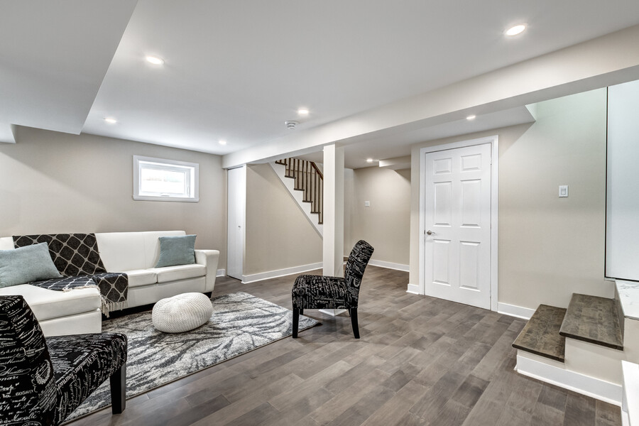 Finished garage conversion with seating area, stairs, and recessed lighting